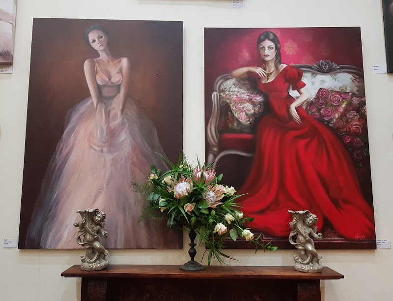 Two large portraits in pride of place above the fireplace in Hannah's Gallery