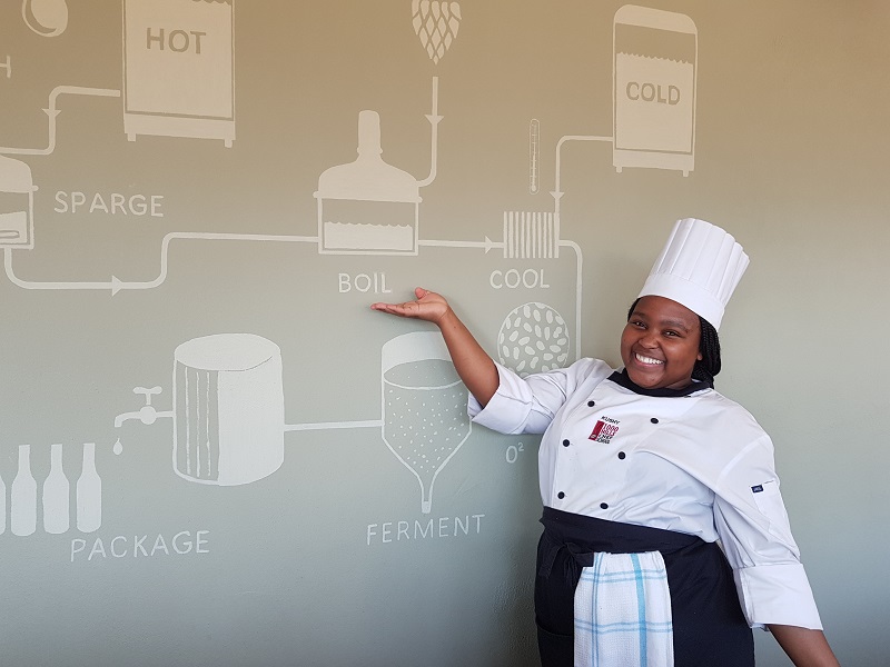 Student, Kushy Manzi shows a wall-chart about the making of craft beer at the 1000 Hills Chef School.